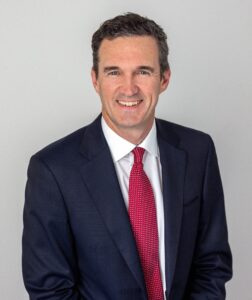 Dr David Morgan wearing dark navy suit and red tie